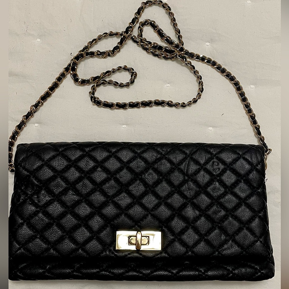 Black quilted fold over clutch with gold hardware. Removable strap. Snap closure